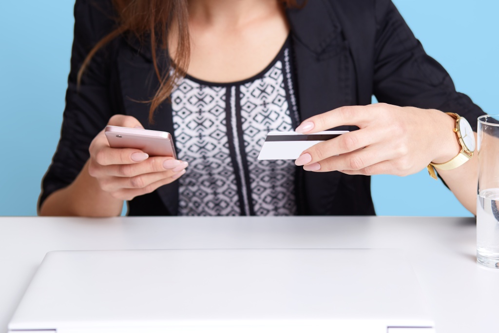 portrait-faceless-woman-wears-black-suit-using-cell-phone-credit-card-while-sitting-white-table-near-laptop-computer-glass-water-isolated-blue-wall-online-payment-concept.jpg телефон
